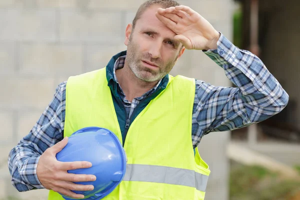 Mężczyzna budowniczy z zmęczony twarz dotyka czoło — Zdjęcie stockowe