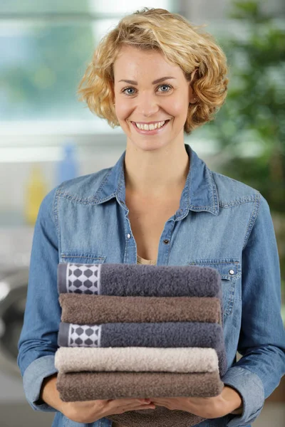 Μια γυναίκα κρατάει καθαρές διπλωμένες πετσέτες. — Φωτογραφία Αρχείου