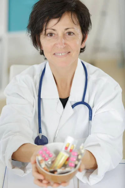 Kobieta lekarz pokazując pigułkę do kamery w konsultacji — Zdjęcie stockowe