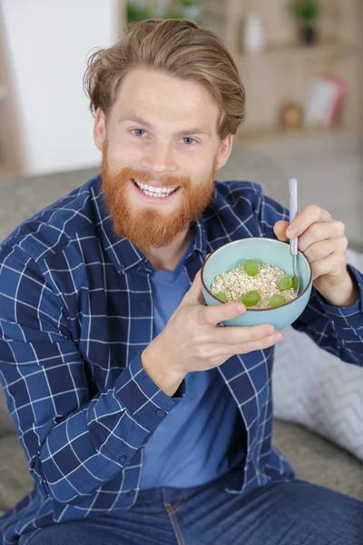 Чоловік показує свій здоровий муселі і виноградний сніданок — стокове фото