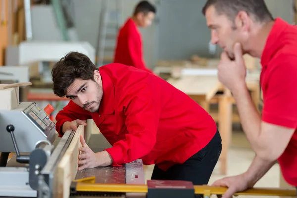 Carpintero que supervisa al aprendiz utilizando maquinaria — Foto de Stock