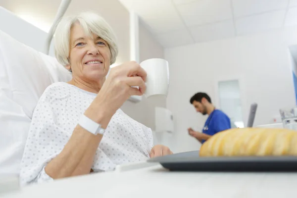 Feliz anciana sosteniendo una taza de café en el hospital —  Fotos de Stock