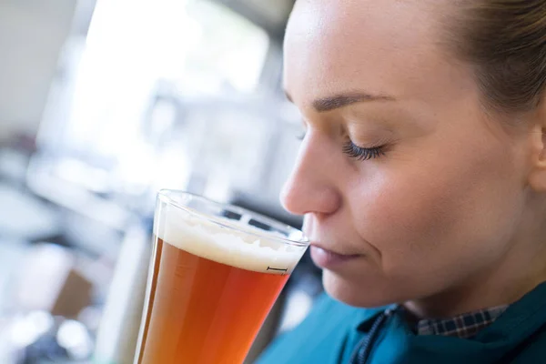 Hermosa cervecera hembra probando cerveza en cervecería — Foto de Stock