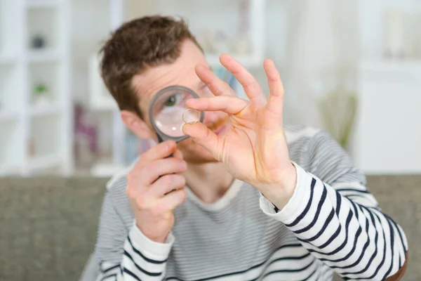 Man looking though a magnifying glass at his coin collection — Stock Photo, Image