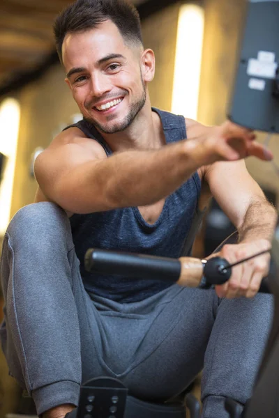 Homme heureux exerçant sur la machine à ramer — Photo