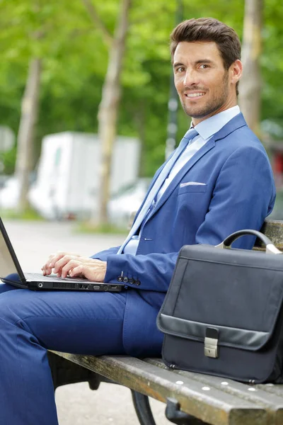 Homem de negócios sentou-se no banco usando laptop — Fotografia de Stock