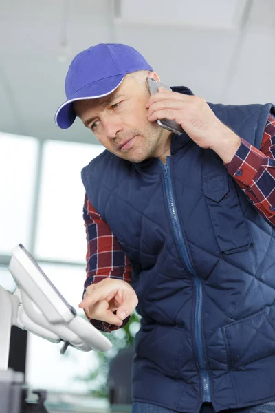 Técnico segurando na impressora de verificação de telefone — Fotografia de Stock