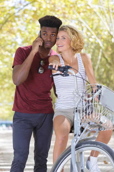 Retrato de una pareja mixta junto a una bicicleta — Foto de Stock