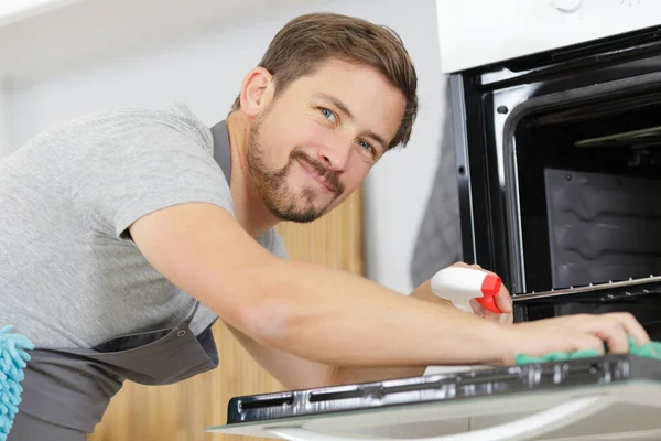 Homem com pano de limpeza dentro do forno em casa cozinha — Fotografia de Stock