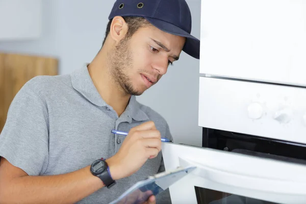 Technician repairing oven in kitchen — Stockfoto