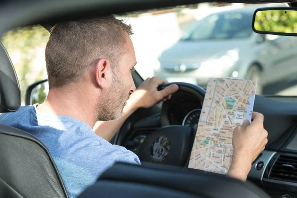 Homme en voiture consultation feuille de route papier — Photo