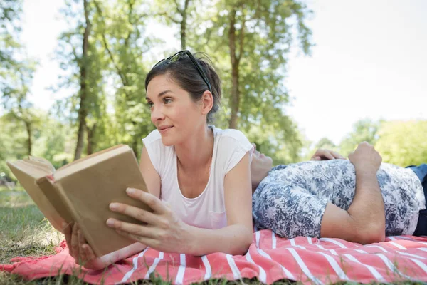 Par på filt utomhus kvinna läser bok man sover — Stockfoto