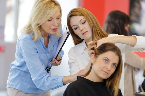 Vacker kvinnlig frisör utbildning på en lärling huvud — Stockfoto