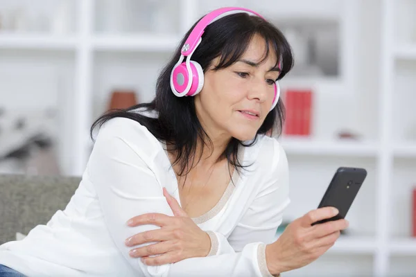 Mujer madura escuchando música a través de los auriculares —  Fotos de Stock