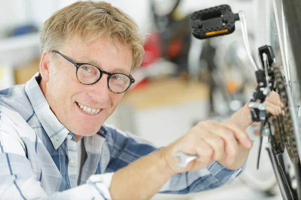 Felice uomo anziano che ripara una ruota della bicicletta — Foto Stock