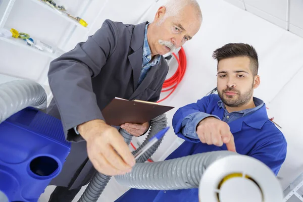 Uomini esaminando tubo di ventilazione — Foto Stock