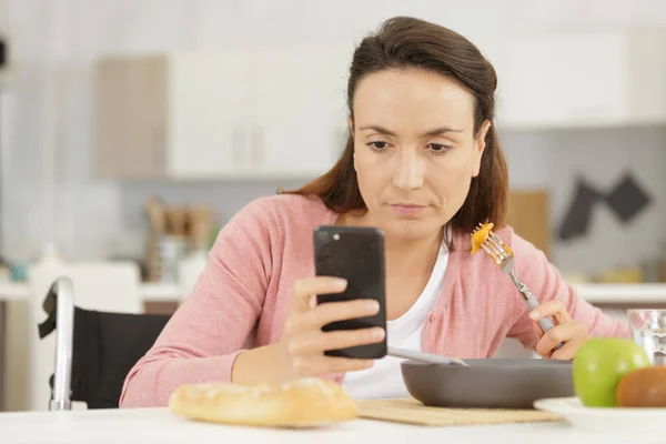 Pensiv kvinna sms:ar medan hon äter — Stockfoto