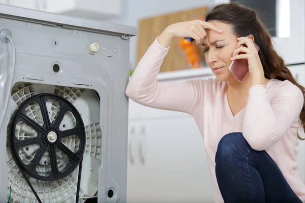 Woman in the washing machine calling for appliance repair service — Stock Photo, Image