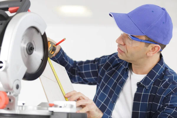 Tischler misst ein Brett, bevor er mit der Kreissäge sägt — Stockfoto