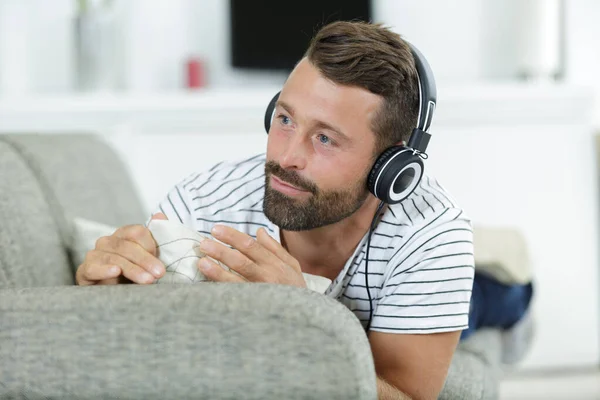 Mężczyzna relaksujący się na kanapie ze słuchawkami — Zdjęcie stockowe