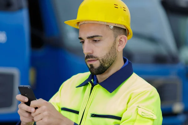 Man with smartphone in front of heavy vehicle — ストック写真