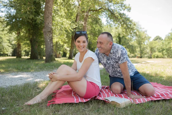 Casal sentado ao ar livre com piquenique sorrindo — Fotografia de Stock