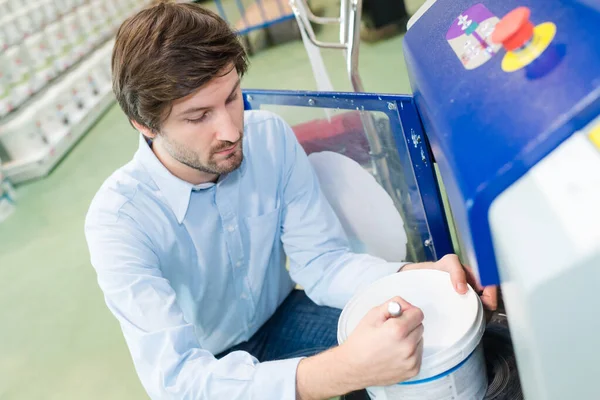 Uomo scrittura colore su vasca di vernice in negozio — Foto Stock