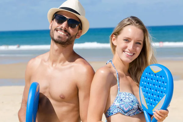 Uomo e donna in posa con racchetta da tennis da spiaggia in plastica — Foto Stock