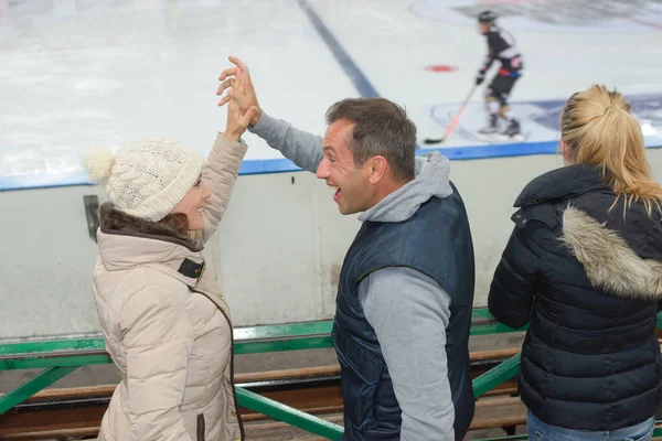 Apoiantes assistindo jogo de hóquei no gelo fazendo um high-five — Fotografia de Stock