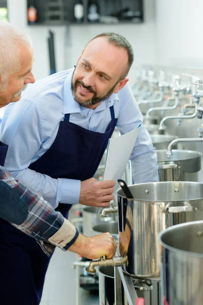 Two seniro men stood by stainless steel vats — Stockfoto