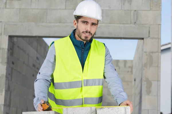 Jovem construtor medindo uma parede — Fotografia de Stock