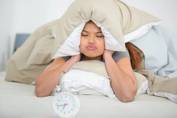 Mujer suspirando y cubriendo los oídos como suena la alarma —  Fotos de Stock