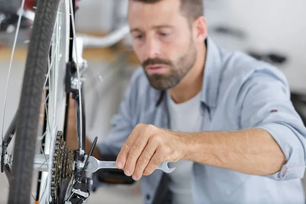 Επαγγελματικός handyman σύσφιξη κεντρικό μπουλόνι του τροχού ποδηλάτου με κλειδί — Φωτογραφία Αρχείου