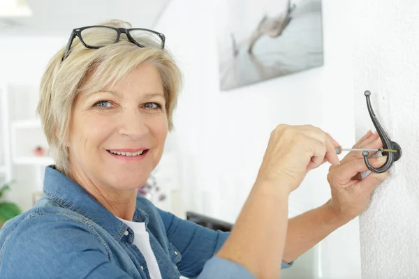 Senior kvinna sätta en krok på väggen — Stockfoto