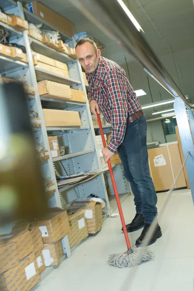 Man mopping floor of warehouse — Stockfoto