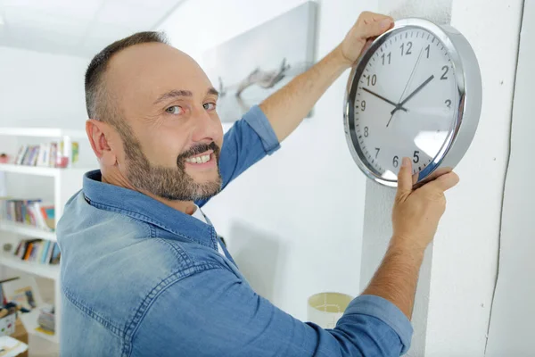 A middle aged man hanging wall clock — Stock Photo, Image