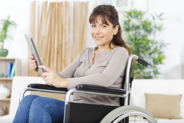 Mujer discapacitada en silla de ruedas en casa con tablet pc —  Fotos de Stock