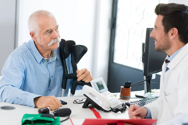 Médecin parler au vieil homme avec des béquilles — Photo