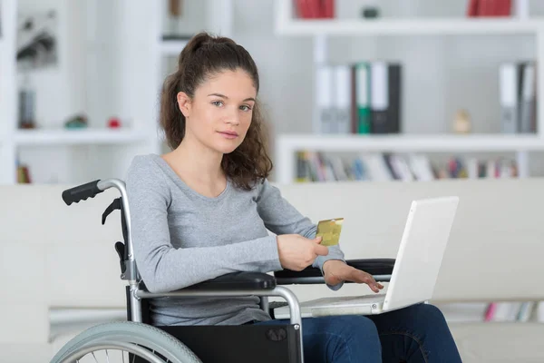 Dizüstü bilgisayarı olan tekerlekli sandalyedeki genç kadın. — Stok fotoğraf