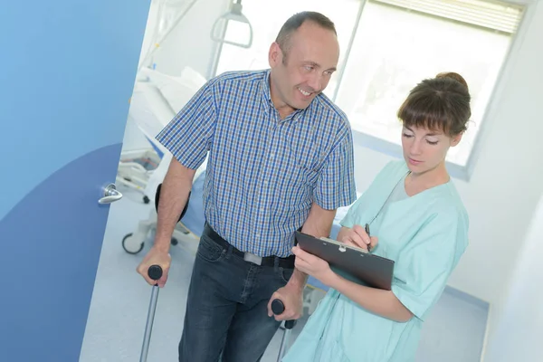 Verpleegster met volwassen man op krukken — Stockfoto