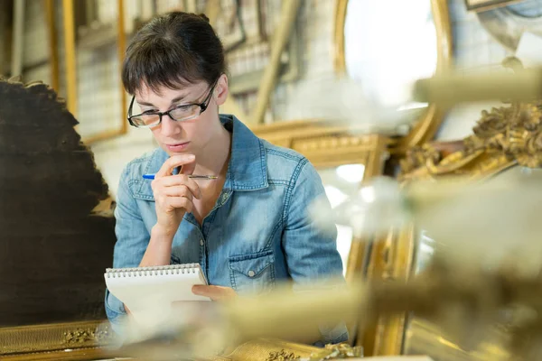 Retrato de antiquário feminino lendo suas notas — Fotografia de Stock