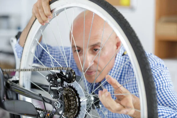 Orta yaşlı satıcı bisiklet tekerleğini tamir ediyor. — Stok fotoğraf