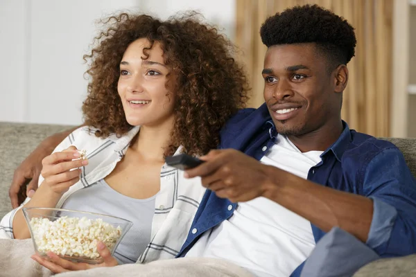 Mladý pár s popcorn na pohovce u filmu — Stock fotografie