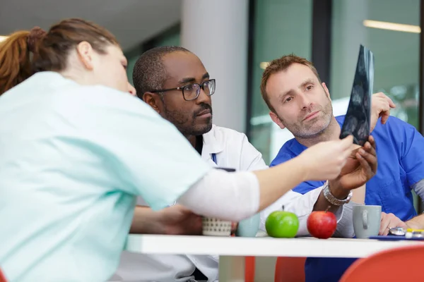 Team of doctors looking to an xray while having lunch — Stock Photo, Image