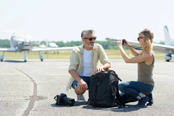 Woman takes a photo of a man in airfield — Stock Photo, Image