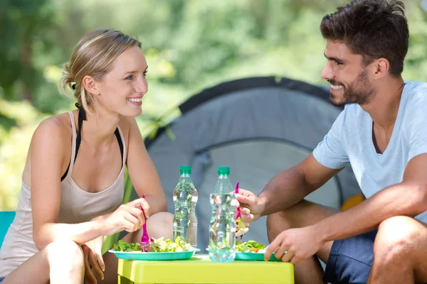 Ett par som kopplar av bredvid ett tält — Stockfoto