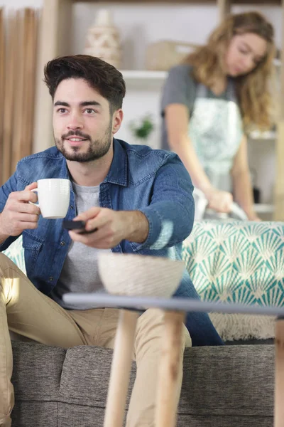 Husband watching tv while wife ironing — Stockfoto