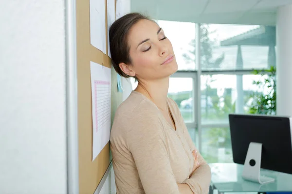 Affärskvinna lutar sig mot väggen på kontoret — Stockfoto