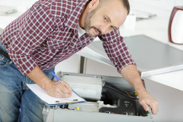 Loodgieter met klembord bij wasmachine — Stockfoto