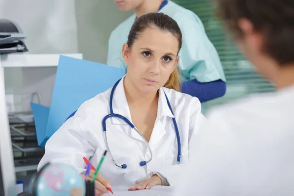 Läkare pratar med patienten och anteckningar — Stockfoto